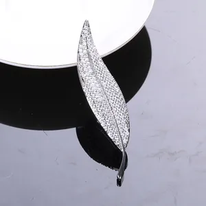 Macro shot of silver leaf brooch with zircon pavé setting on reflective black surface