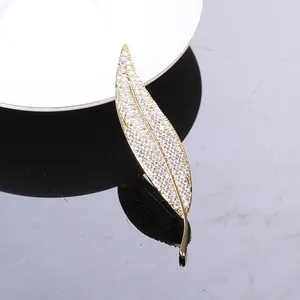 Macro shot of leaf-shaped brooch featuring golden veins and pave-set white cubic zirconia