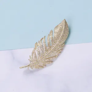 Detailed close-up of a golden feather brooch with shimmering zircon pave setting
