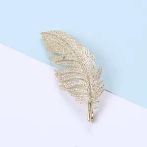 Detailed view of feather brooch with inlaid zircons and golden finish texture