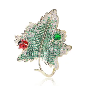 Détail de la broche feuille avec pierre verte en goutte et coccinelle sur base dorée