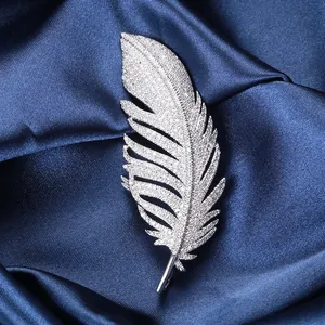 Close-up of feather brooch with zircon stones on elegant blue silk background