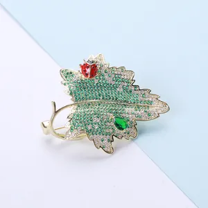 Détail de la broche feuille avec zircons verts, coccinelle rouge et gemme émeraude