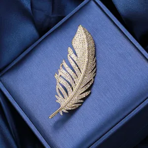 Macro shot of elegant gold feather brooch with shimmering pavé zircon details on silk