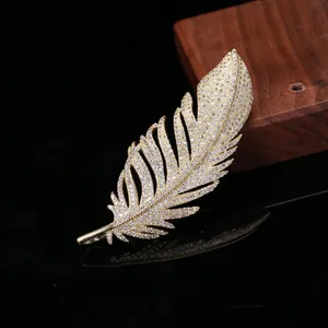 Macro shot of elegant golden feather brooch featuring detailed zircon pavé setting