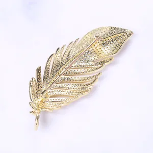 Close-up of golden feather brooch back showing needle pin structure and texture