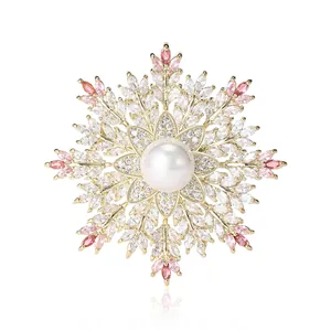 Elegante spilla a fiocco di neve con zirconi e perla su base in metallo dorato lucido