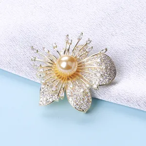 Dettaglio macro della spilla a orchidea con zirconi pavé e perla dorata centrale