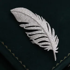 Elegant silver feather brooch with sparkling zircons on a green velvet jewelry box