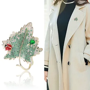 Broche feuille dorée élégante avec zircons verts et coccinelle sur revers beige