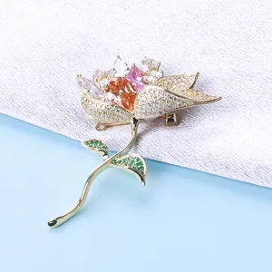 Detail of elegant gold lotus brooch with amber and pink zircon petals on fabric