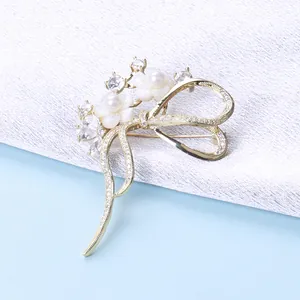 Detail einer eleganten Goldbrosche mit Zirkonschleife, Muschelblumen und Perlen