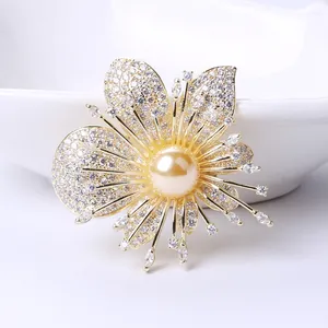 Dettaglio della spilla orchidea con petali dorati, pavé di zirconi e perla centrale
