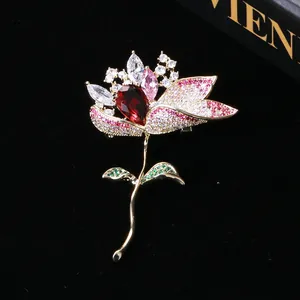 Detail of a lotus brooch featuring a large red teardrop gemstone and pink zircon petals