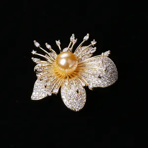Dettaglio macro della spilla orchidea con perla dorata e zirconi su sfondo in velluto nero