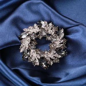 Makroaufnahme einer silbernen Ringbrosche mit grauen Kristallen auf blauem Seidengrund