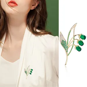 Elegant gold lily of the valley brooch with micro-set green crystals and white zircon stones