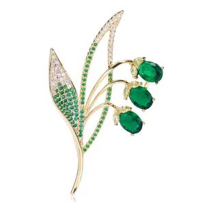 Detailed close-up of zircon bell orchid brooch with green gems and golden metal finish