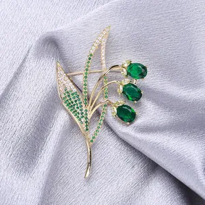 Elegant gold lily of the valley brooch with micro-paved emerald green zircon stones