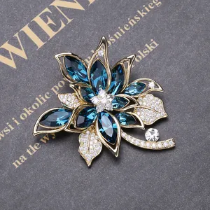 Macro detail of luxury flower brooch with blue marquise crystals and golden petals