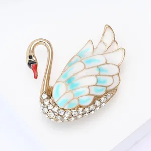 Detail view of gold alloy swan brooch with enamel wings and sparkling rhinestones