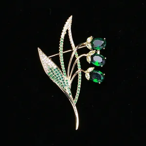 Macro shot of lily-of-the-valley brooch with green oval stones and pave-set zircons