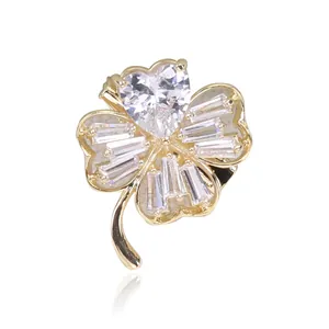 Detail of four-leaf clover brooch with heart and baguette cut crystals in gold setting
