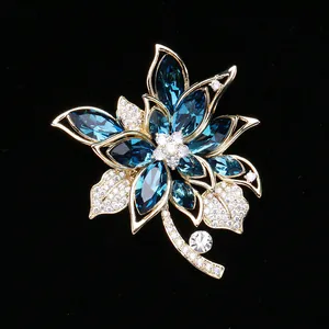 Detailed close-up of a floral brooch with blue marquise stones and gold-tone finish