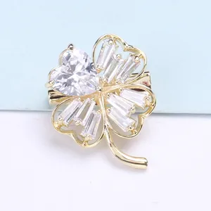 Macro detail of golden clover brooch with heart-cut and baguette-cut cubic zirconia