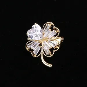 Detailed shot of a gold four-leaf clover brooch with heart-cut and baguette zircon stones