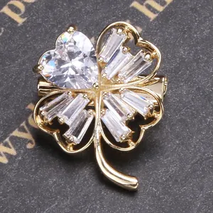 Macro shot of gold clover brooch with heart-shaped and baguette-cut cubic zirconia crystals