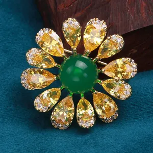 Elegant vintage sunflower brooch with emerald green gem and yellow petals on dark background