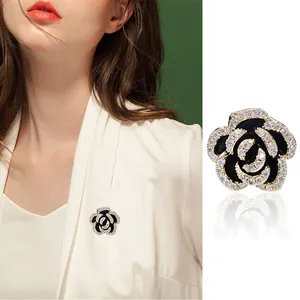 Elegant camellia flower brooch with black enamel petals and micro-set cubic zirconia accents