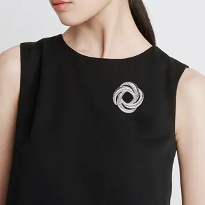 Close-up of geometric silver knot brooch with spiral texture on black fabric