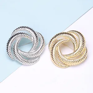 Macro detail of geometric twisted spiral brooches in gold and silver alloy finishes