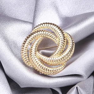 Detailed view of intertwined golden rings brooch with intricate textured line patterns