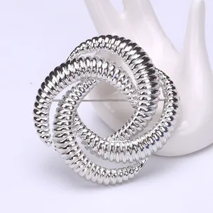 Detailed macro view of silver geometric spiral brooch with fine textured surface details