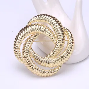 Detailed view of large gold intertwined rings brooch with fine threaded texture and pin back