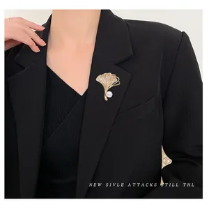 Elegante goldene Ginkgo-Brosche mit Perlen und Zirkon auf einem schwarzen Blazer