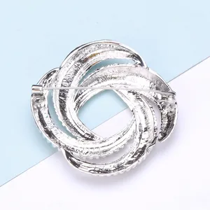 Detail of silver geometric brooch with spiral ring design and metal pin fastening