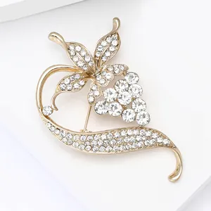 Gros plan d'une élégante broche de vigne dorée avec des strass blancs et courbes florales
