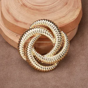 Detailed close-up of a gold triple-twisted knot brooch with fine textured surface