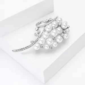 Detailed close-up of luxury pearl brooch with silver leaf design and crystal inlay