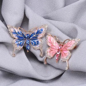 Detail of blue and pink enamel butterfly brooches with rhinestones on grey fabric