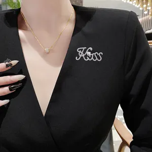 Elegante set di spilla Kiss con strass e collana dorata su un vestito nero