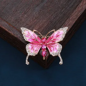 Macro detail of enamel butterfly brooch with pink rhinestones on a wooden stand
