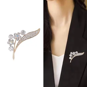Elegant gold-tone flower and feather brooch with crystal rhinestones on a black suit