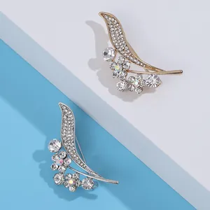 Elegant gold and silver rhinestone leaf brooches with aurora crystals on a tiered background