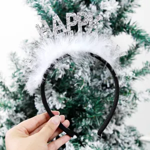 Close-up of a festive headband with fluffy white feathers and silver glittery Happy text