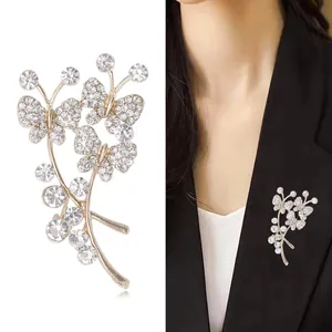 Broche papillon dorée élégante avec cristaux sur fond blanc et portée par un mannequin